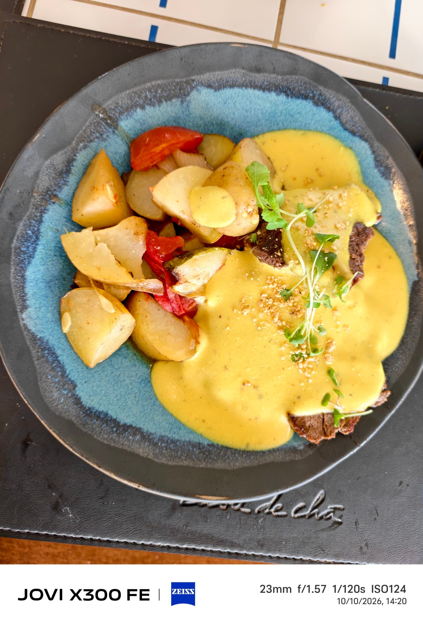 Prato principal com molho amarelo, batatas e vegetais.