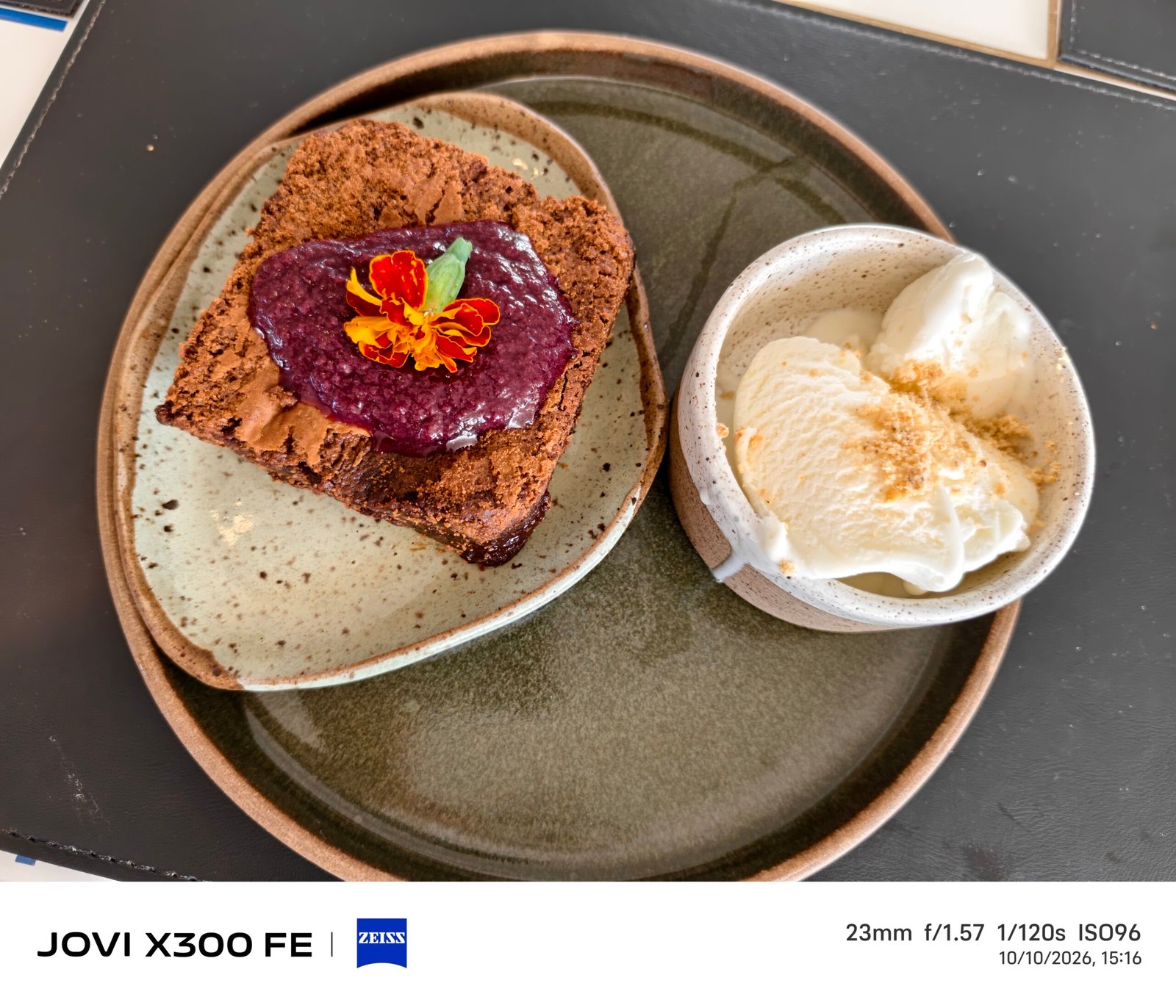 Sobremesa com cobertura de cor roxa e flor, acompanhada de sorvete.