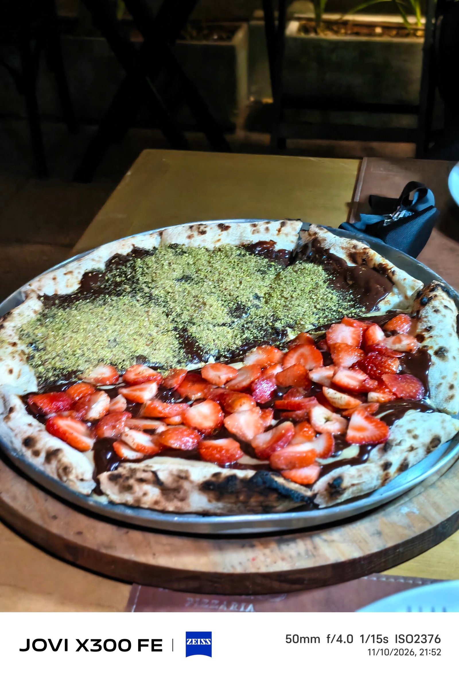 Pizza doce com chocolate, morangos e cobertura triturada.